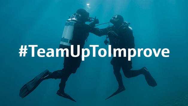 Underwater scene: a diver supports a second diver who experiences issues with the air supply.